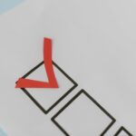 Close-up of a red check mark on a crisp white paper with black boxes, symbolizing completion.